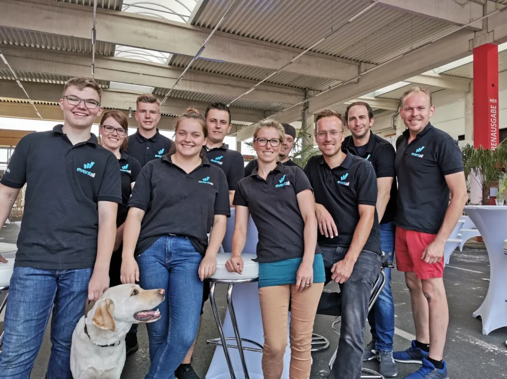 Das Eventall-Team mit Bürohund in der Lagerhalle